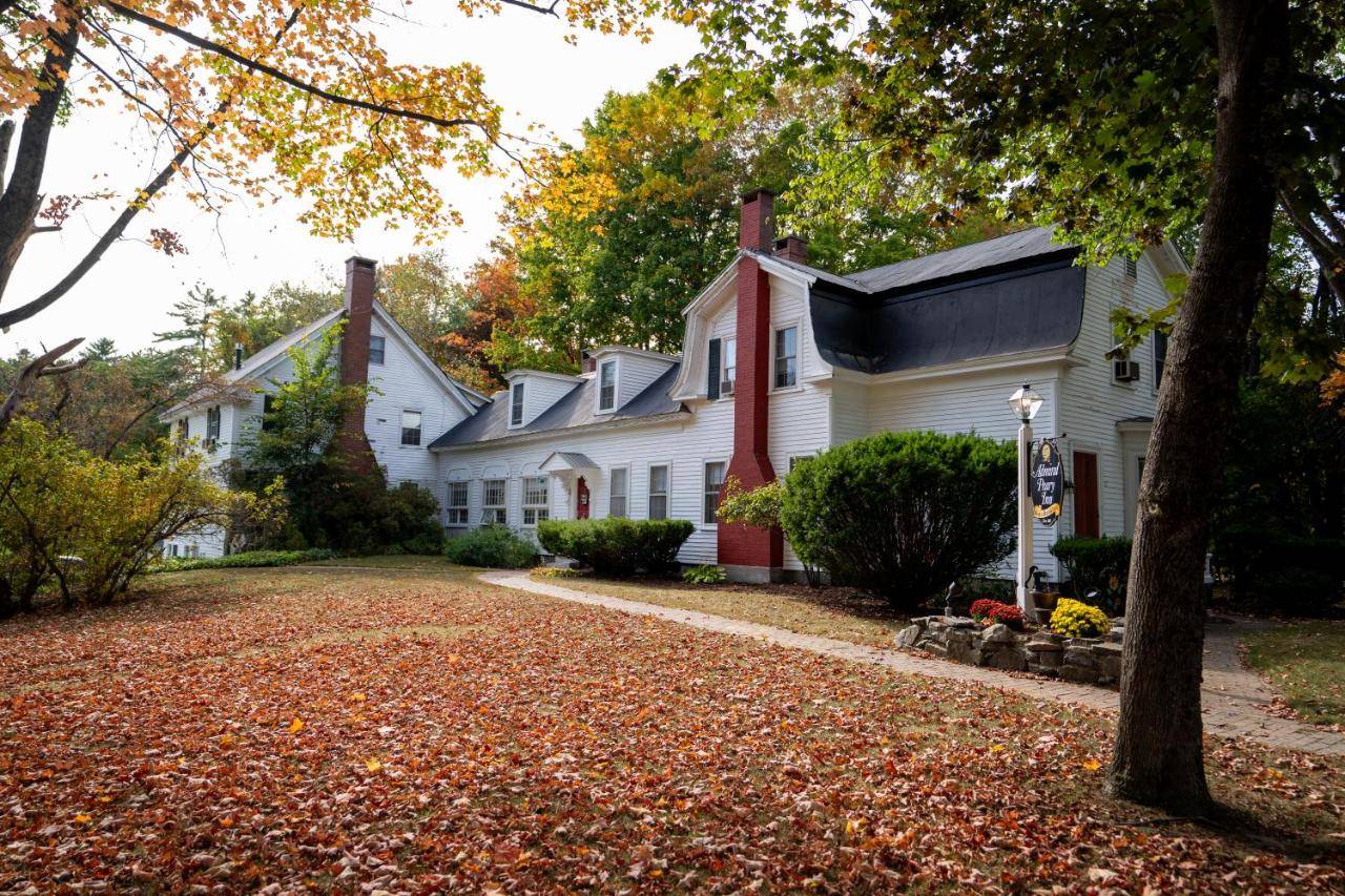 a row of white houses with trees and leaves at Admiral Peary Inn in Fryeburg