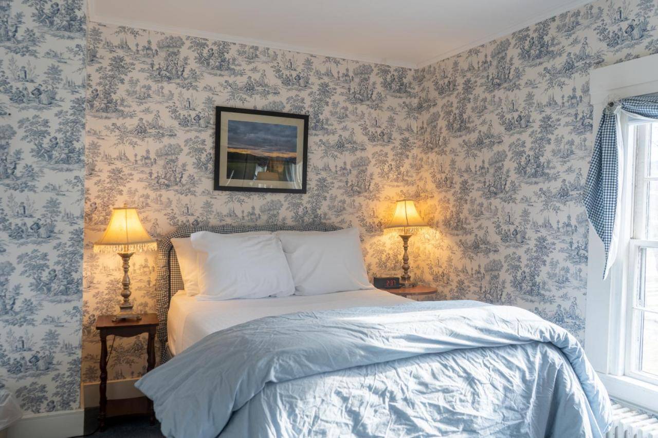 a bedroom with a bed with blue wallpaper at The White Gables Inn in Fryeburg