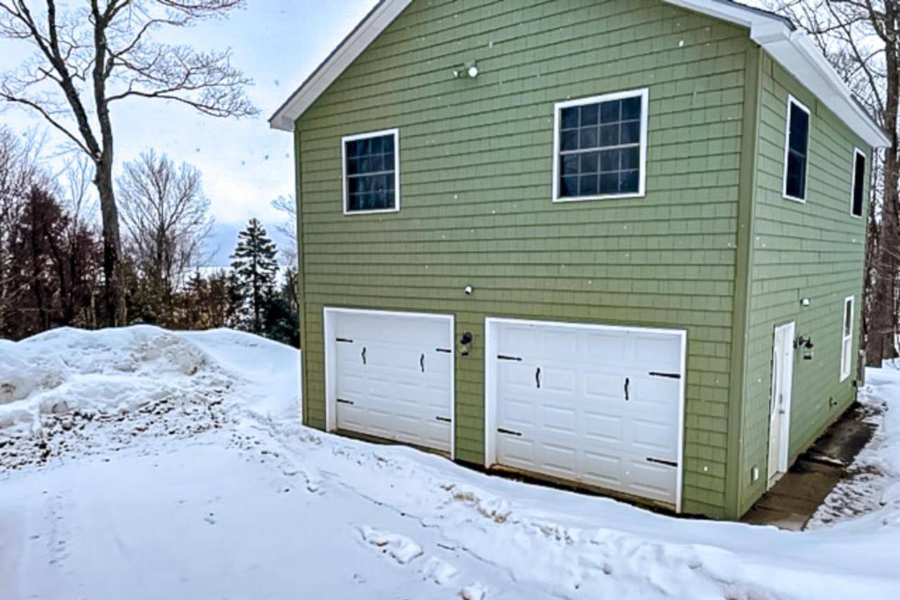 a green house with two garage doors in the snow at Lake Adventures in Greenville