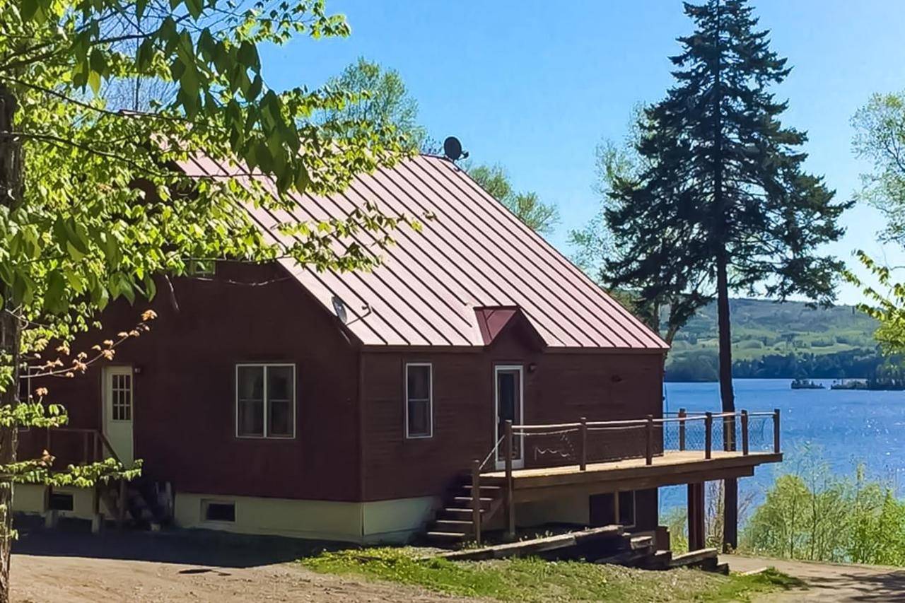 a red house with a dock next to a lake at Moosehead Lodge in Greenville