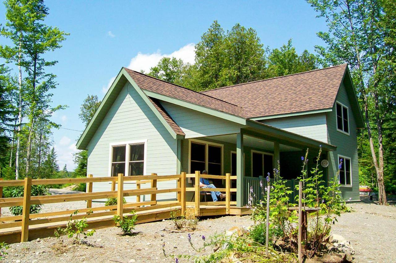 a green and white house with a wooden fence at Sunrise Cottage in Greenville