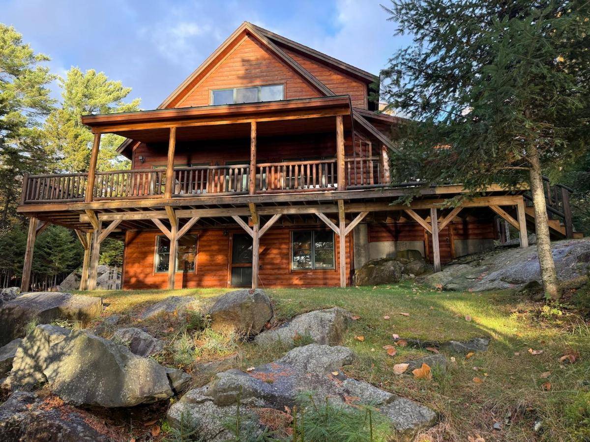 a log cabin with a deck on a mountain at Tranquil Lakefront Getaway on Moosehead Lake in Greenville