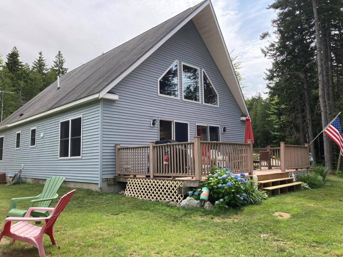 a blue house with a porch and a deck at Oceanfront Hancock Cottage in South Hancock