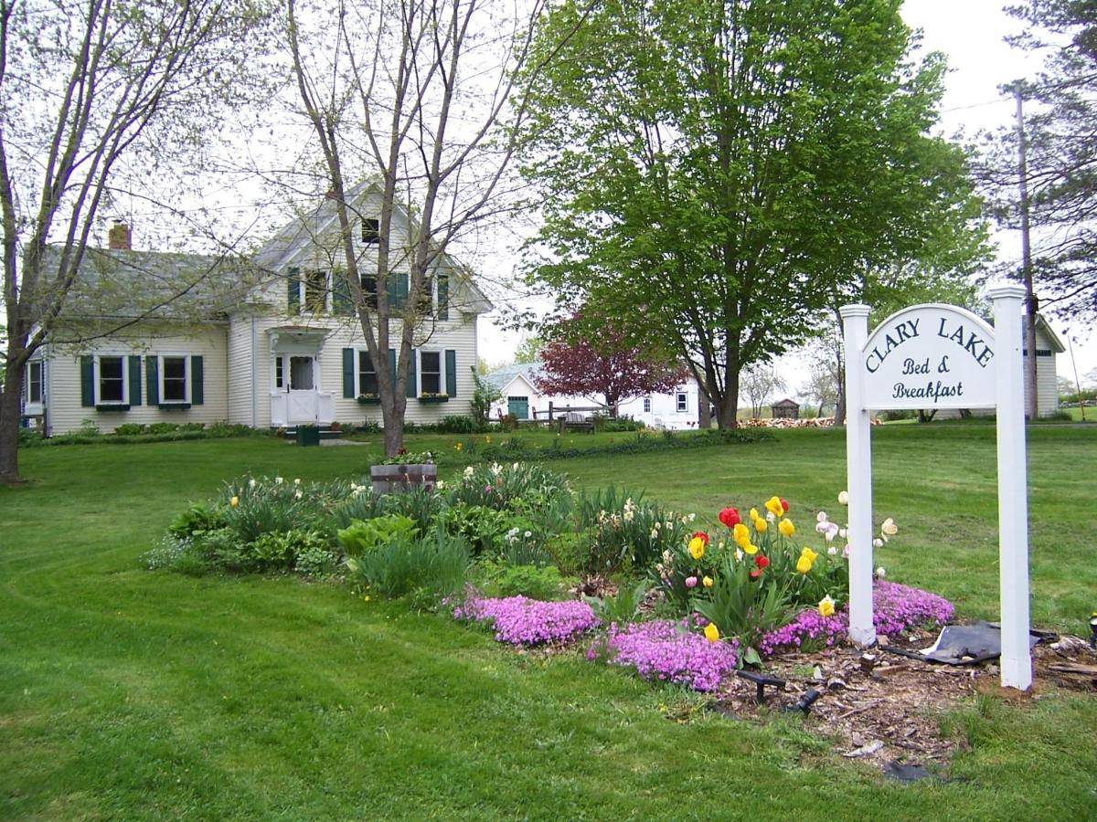 a sign in a garden with flowers in front of a house at Clary Lake Bed and Breakfast in Jefferson