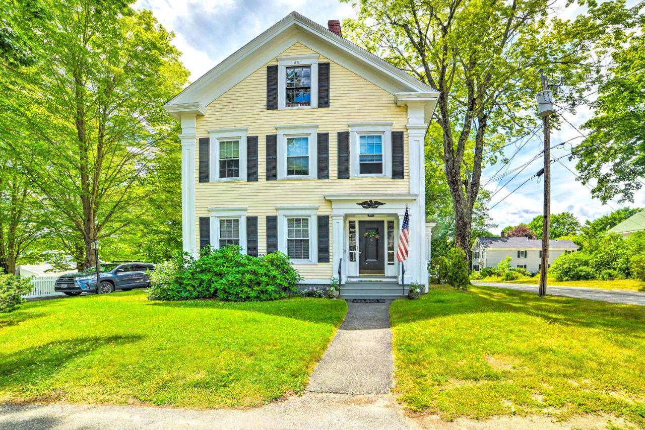 a yellow house with a flag in the front yard at Kennebunk Apartment with Local Beach Access! in Kennebunk