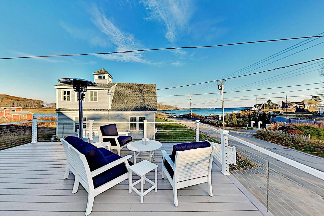 a porch with chairs and a table and a view of the ocean at Thisgood Cove on Turbats Creek in Kennebunkport