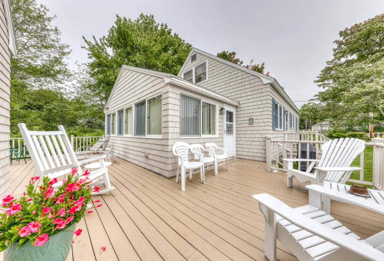 a deck with white chairs and a house at Y Go By in Kennebunkport