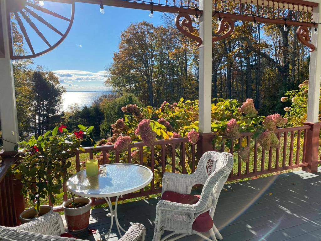 a porch with a table and chairs and flowers at Victorian by the Sea in Lincolnville