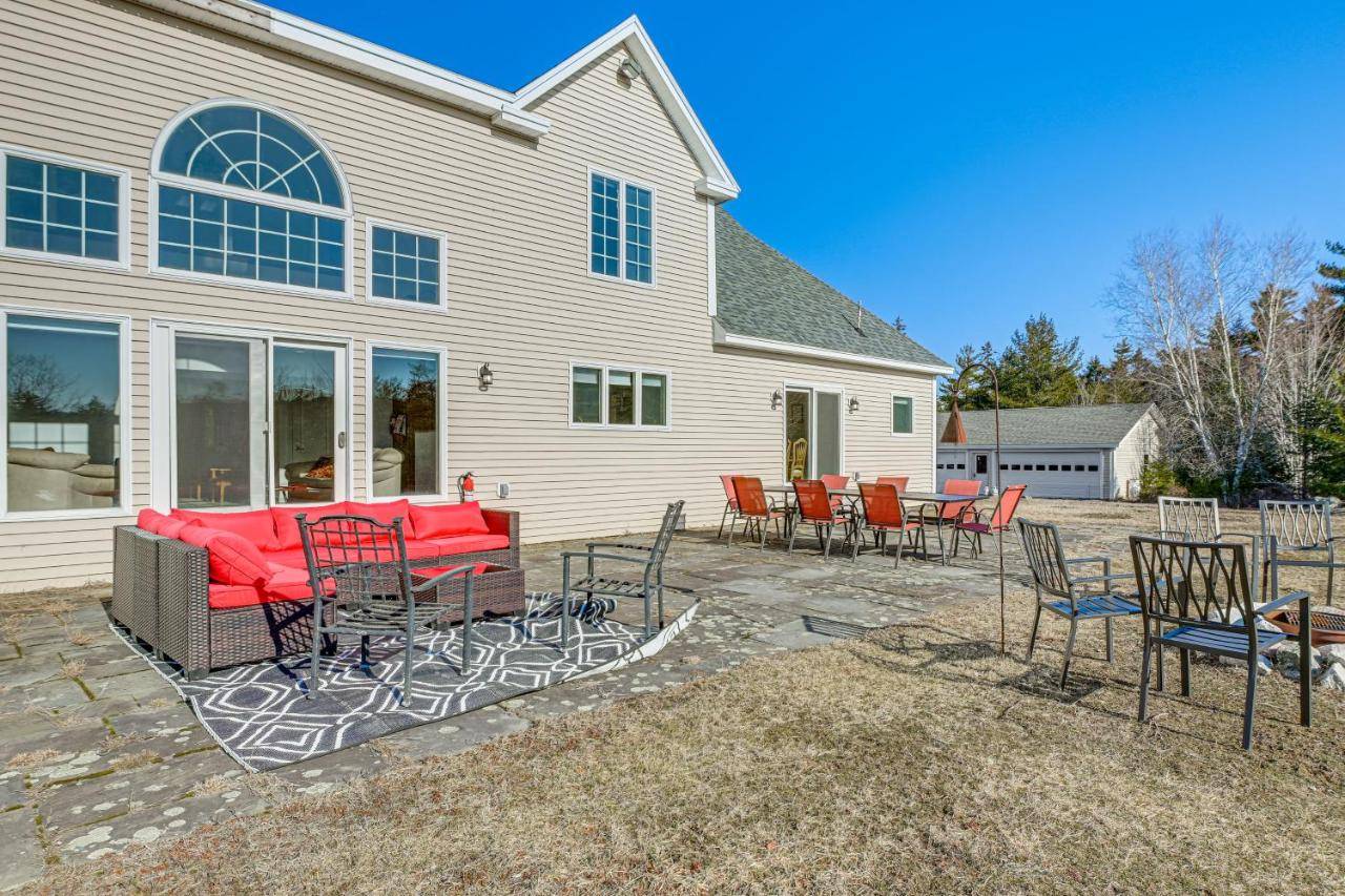 a patio with chairs and tables in front of a house at Acadia Adventure Base 4,500-Sq-Ft Group Getaway in Somesville