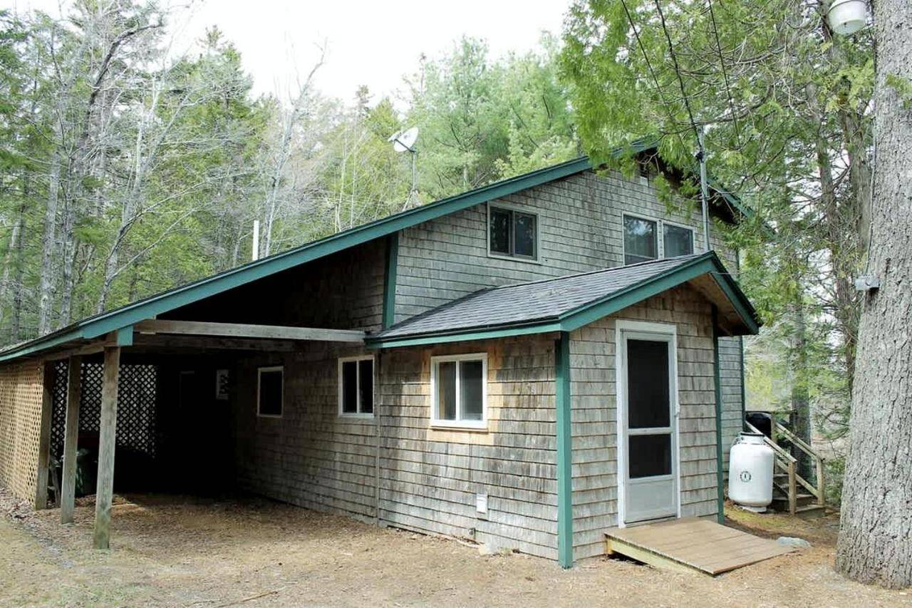 a small house with a garage in the woods at Charming Waterfront Cottage with Scenic Views, canoe Access, Near Bar Harbor, Mount Desert Island, Maine in Somesville