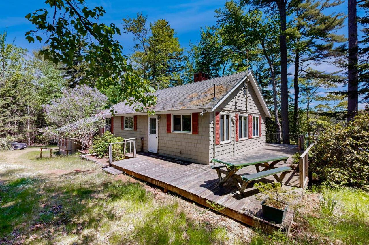 a tiny house with a wooden deck and a picnic table at Ladyslipper Cottage in Somesville