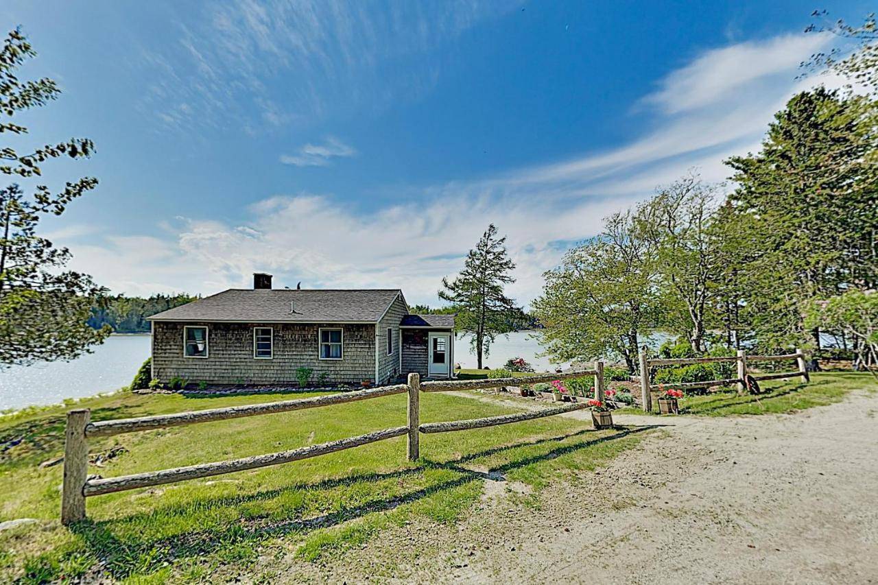 a house on a hill with a wooden fence at Noonie's Nest Waterfront Cottage on Mount Desert Isle in Pretty Marsh