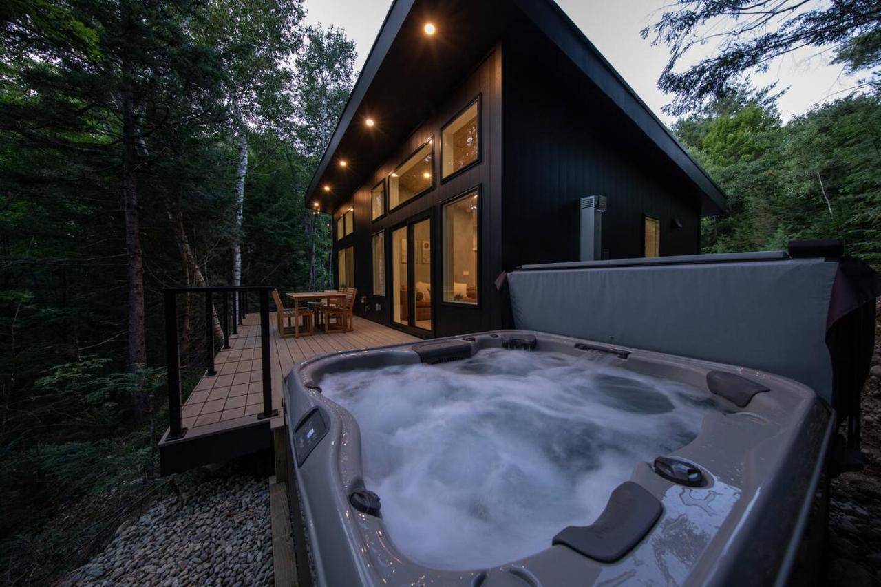 a jacuzzi tub in front of a house at Cozy Luxury Cabin w Hot Tub, Fire Pit, King Bed in Newry