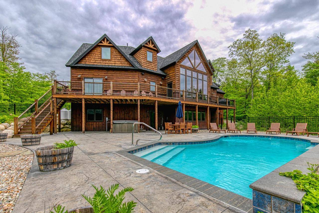 a log house with a pool in front of it at Mountain Estate Family Getaway in Newry