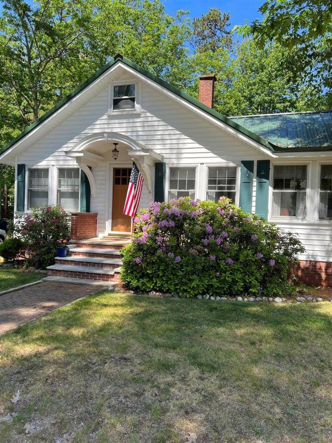 a white house with an american flag on it at MAINE STAY LAKE HOUSE-LIMIT12 home in North Sebago