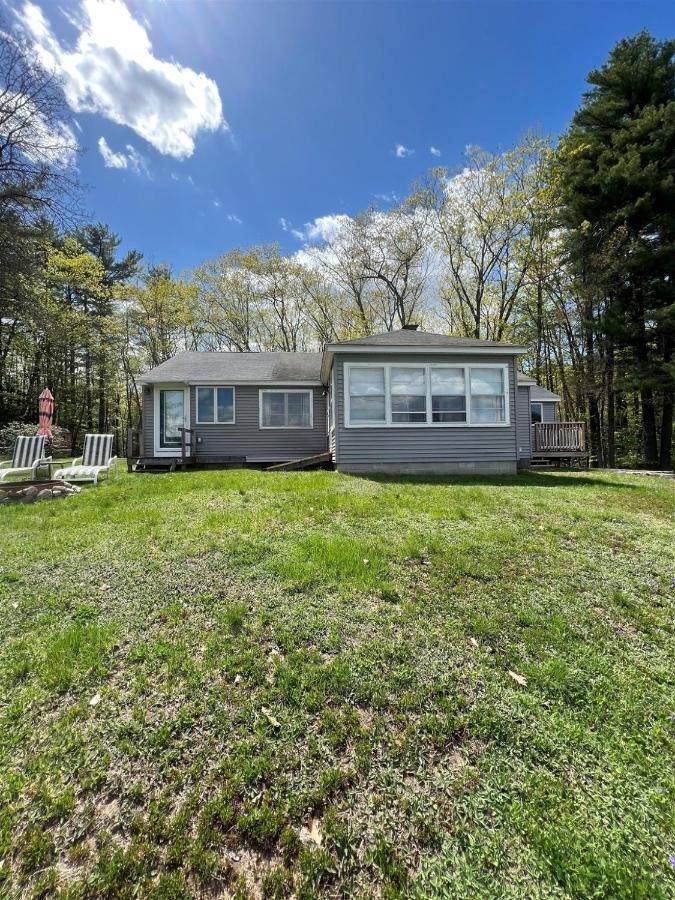 a house on a grassy yard with a house at MARY'S LAKEVIEW - LIMIT 10 home in North Sebago
