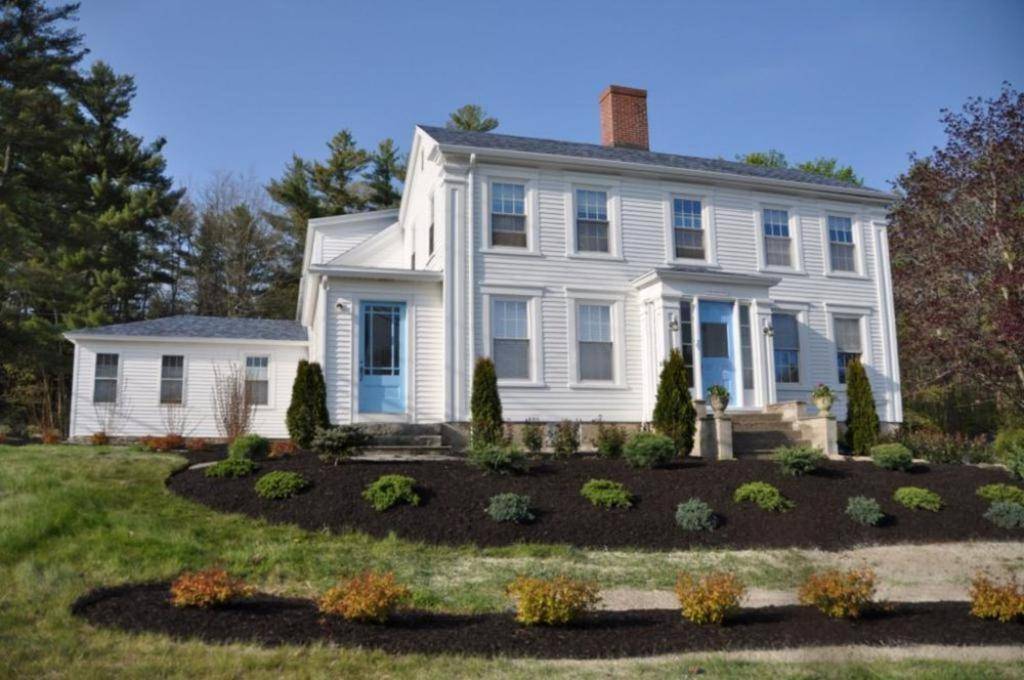 a white house with a garden in front of it at 2 River Road Inn & Cottages in Cape Neddick