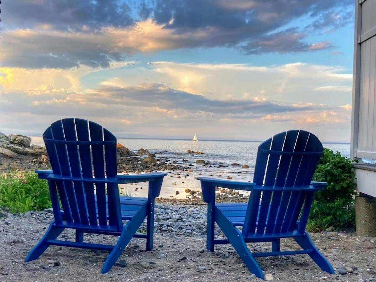 two blue chairs sitting on the beach near the ocean at Perkins Cove Oceanfront Cottage in Ogunquit