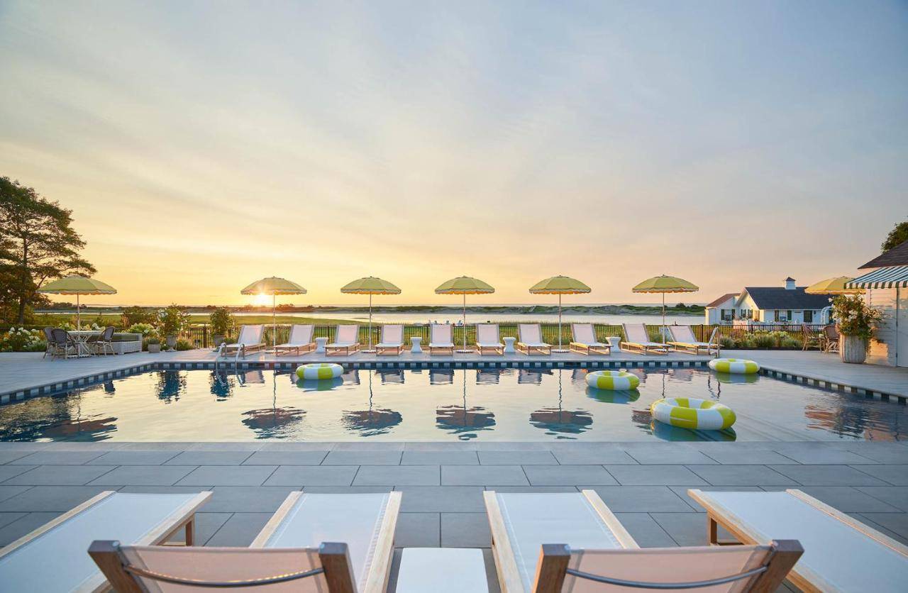 a swimming pool with chairs and umbrellas at The Dunes on the Waterfront in Ogunquit