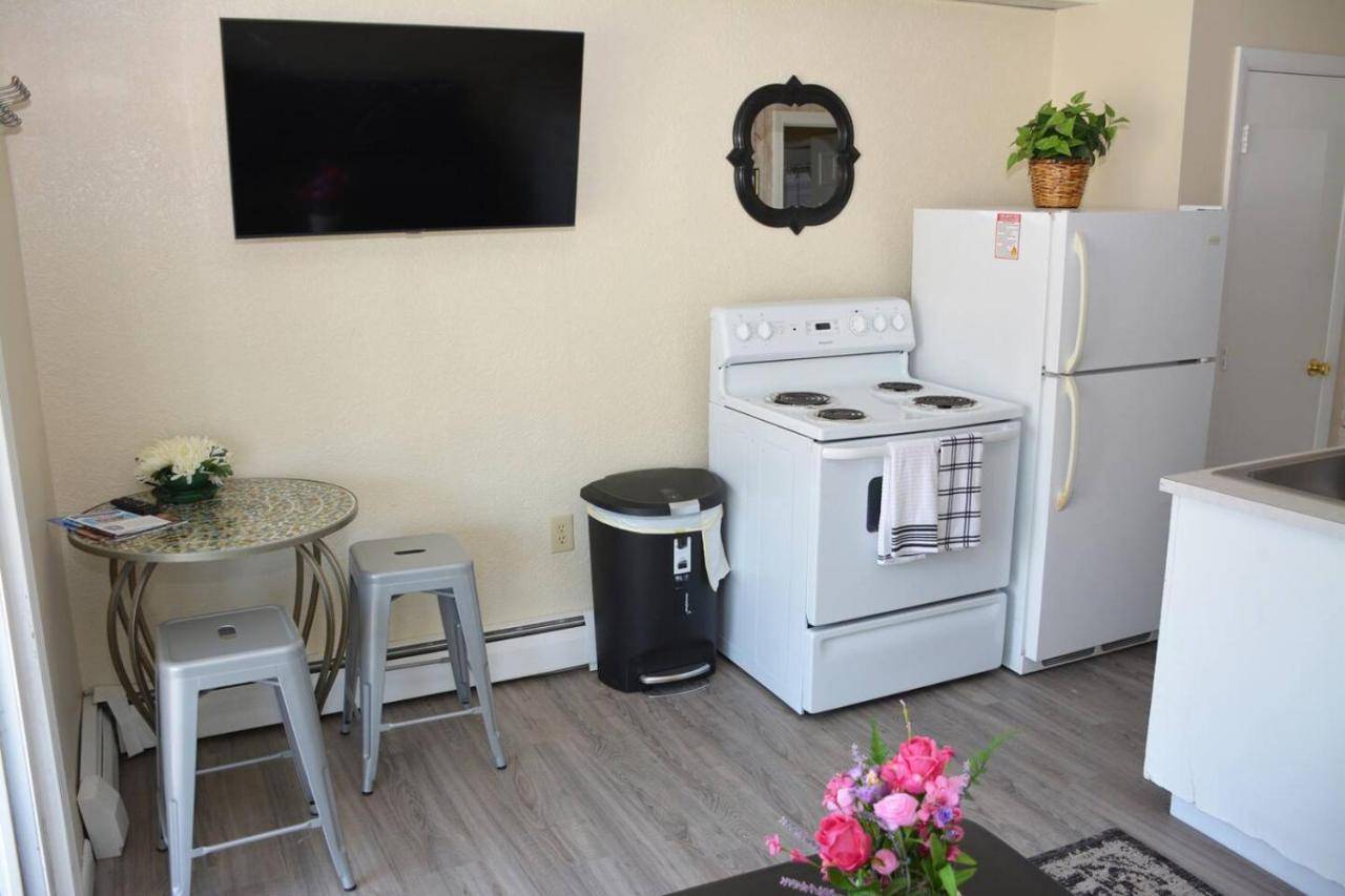 a kitchen with a white refrigerator and a table with stools at 68 East Grand 1 - One-Bedroom Suite by the Beach in Old Orchard Beach