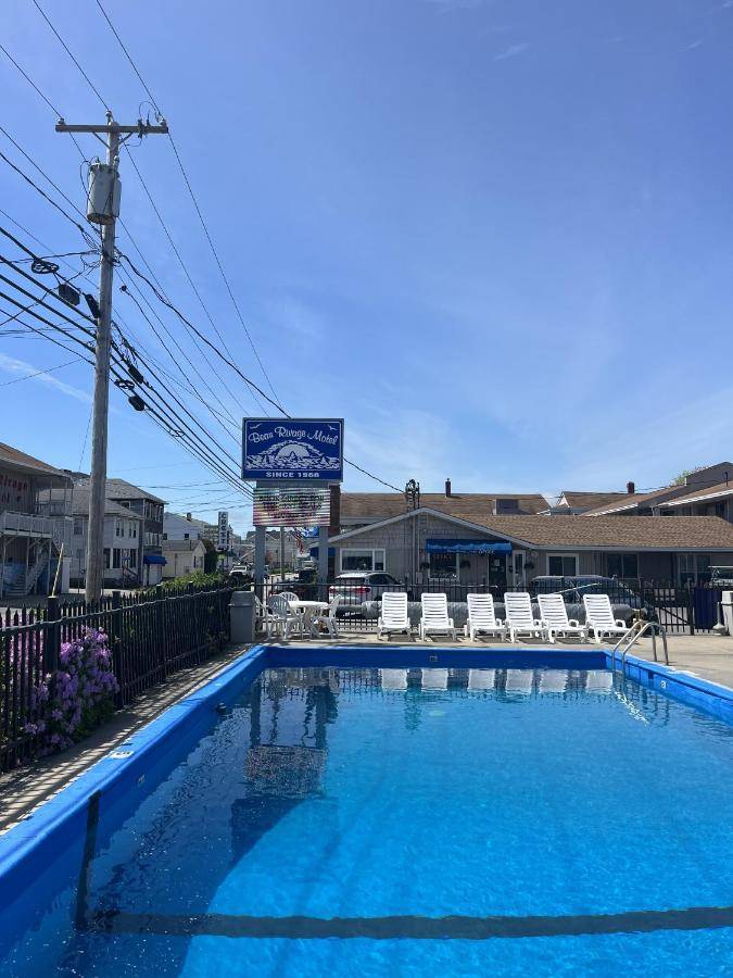 a large blue swimming pool with chairs and a building at Beau Rivage Motel in Old Orchard Beach
