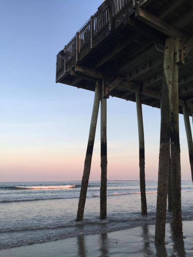 a pier on the beach at sunset at Copley LaReine Motel in Old Orchard Beach