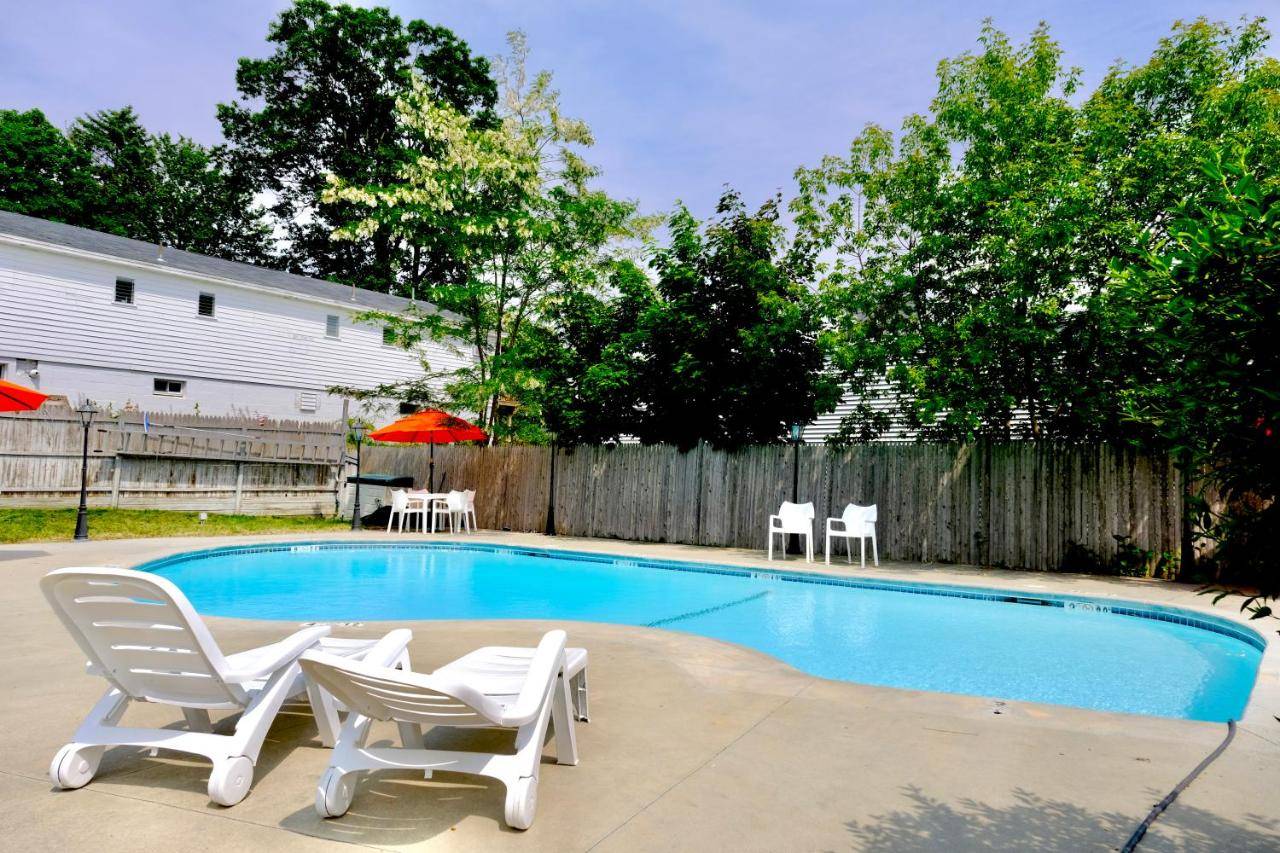 a swimming pool with two white chairs and a table at Dock House Inn in Old Orchard Beach