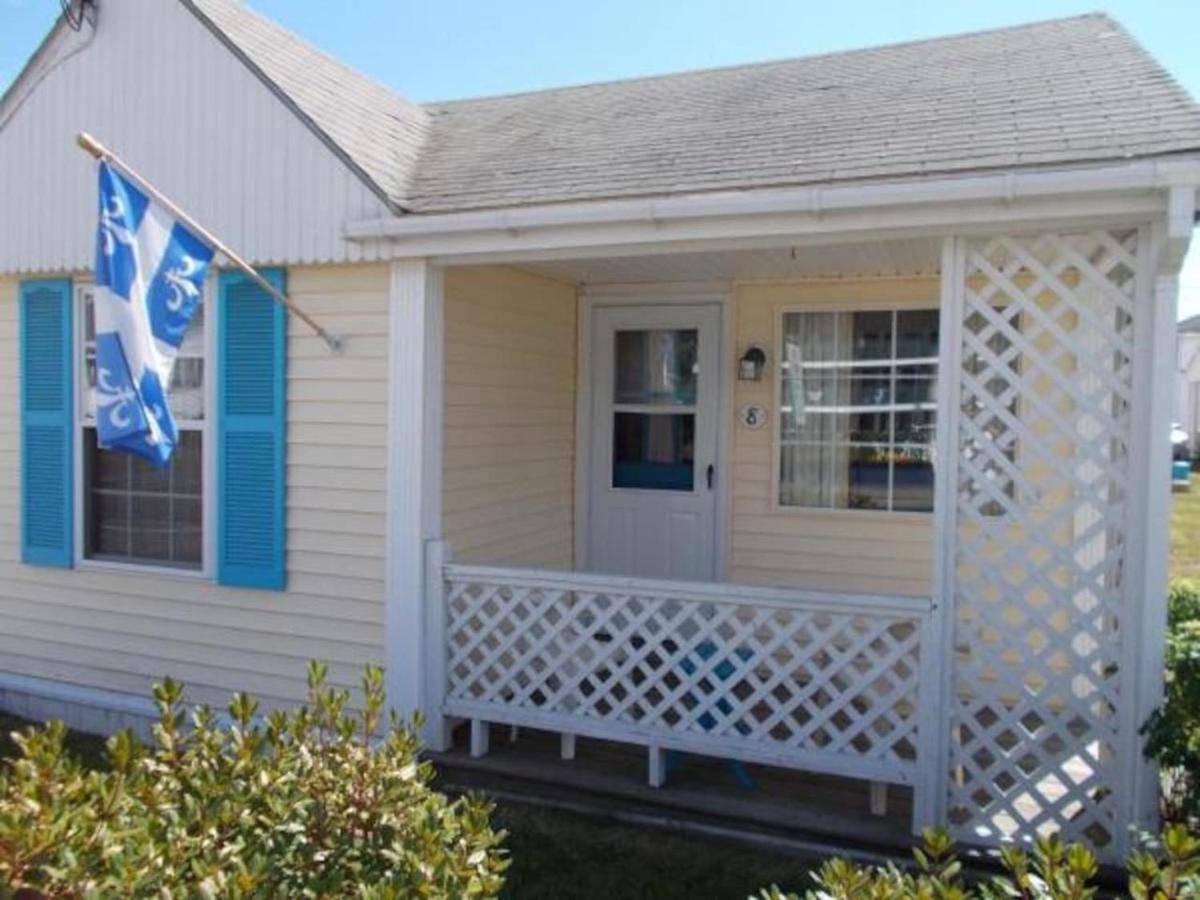 a small house with a porch and a flag at Little Miss Cottages - Two Bedroom Cottage in Old Orchard Beach