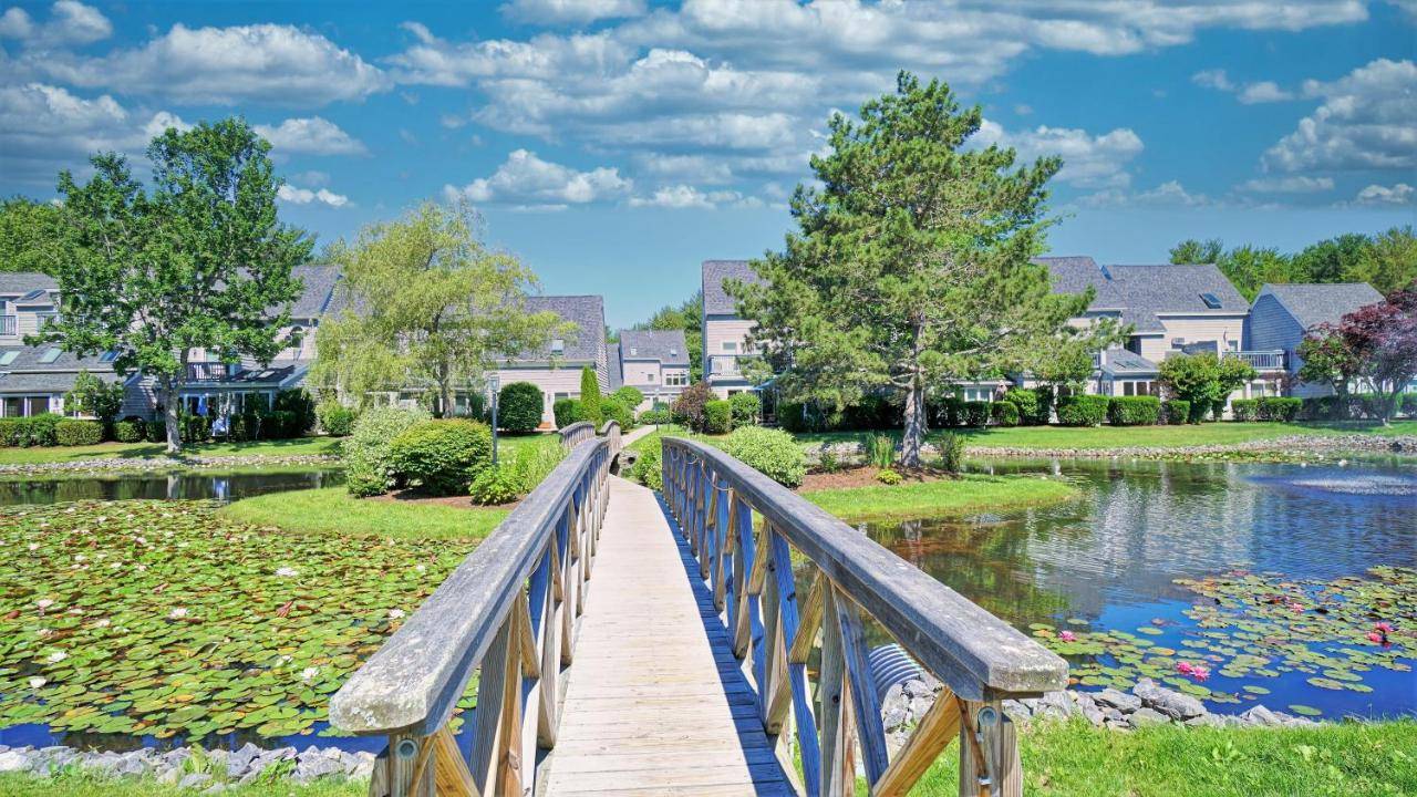 a wooden bridge over a pond in a residential neighborhood at Ocean Park Meadows #93 by Bayley Vacation Rentals in Old Orchard Beach