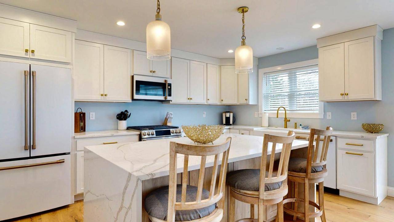 a kitchen with white cabinets and a kitchen island with bar stools at On Par for the Beach by Bayley Vacation Rentals in Old Orchard Beach