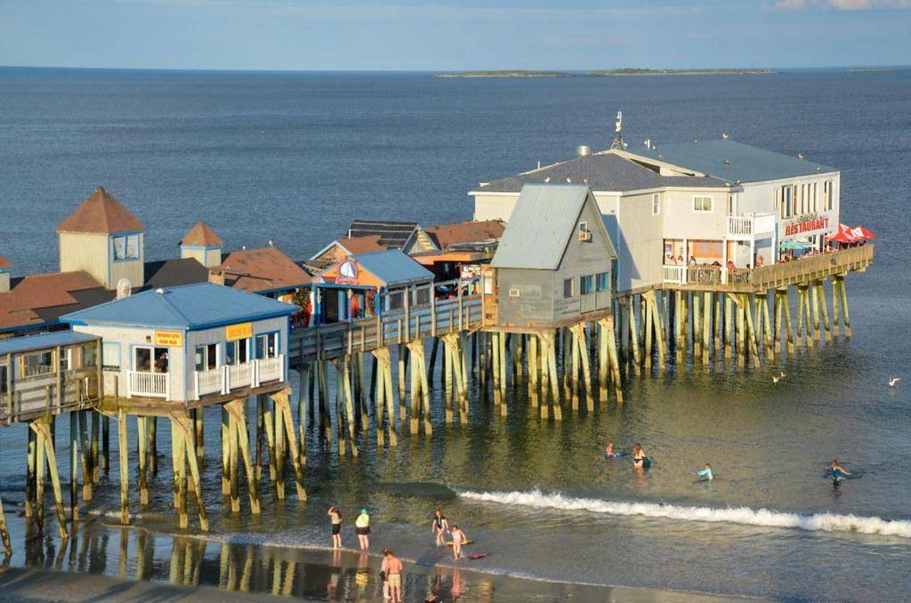 a group of people in the water near a pier at Promenade Deck 202 in Old Orchard Beach