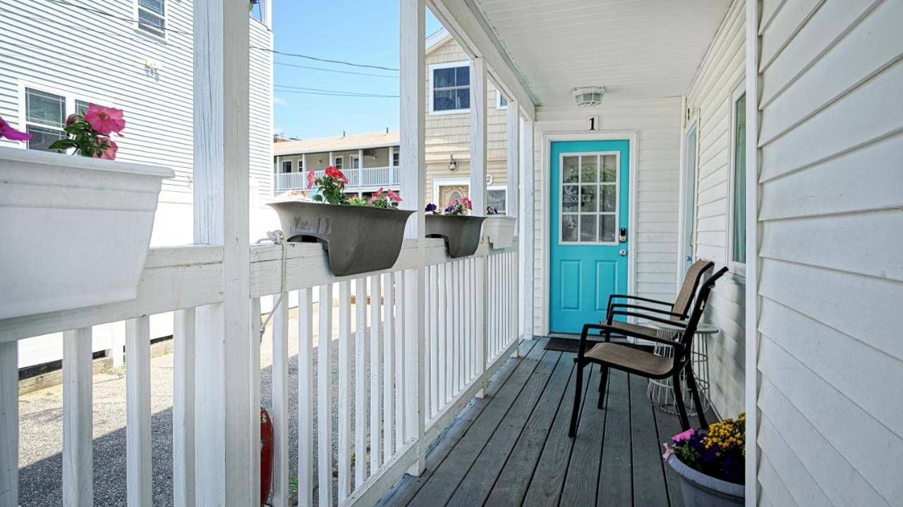 a porch of a white house with a blue door and a chair at Salt Life #1 by Bayley Vacation Rentals in Old Orchard Beach