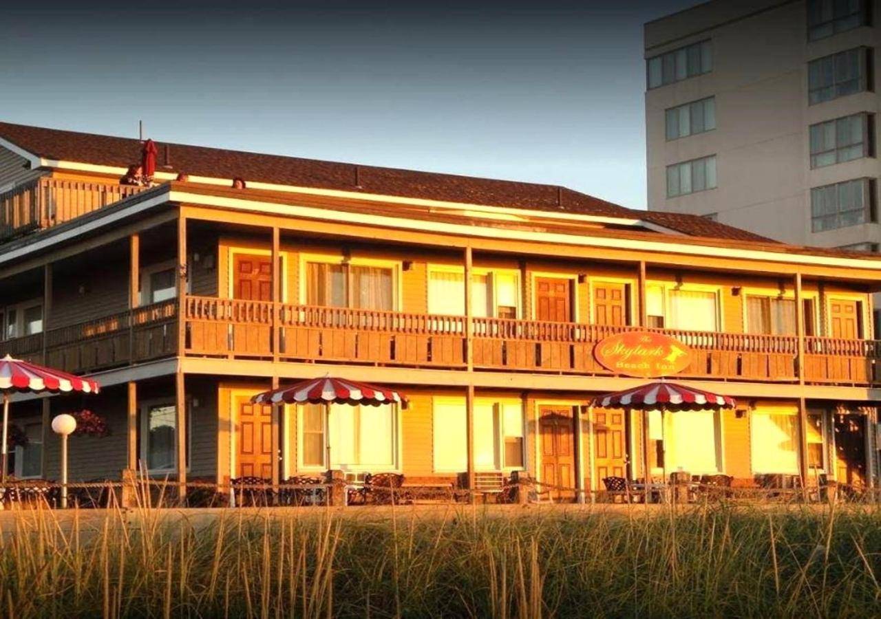 a building with tables and umbrellas in front of it at The Skylark Beach Inn in Old Orchard Beach