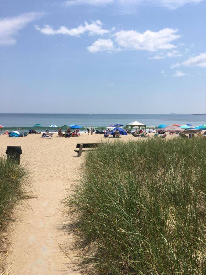 a sandy beach with a bench and umbrellas on it at White Cap Village Unit 6 in Old Orchard Beach