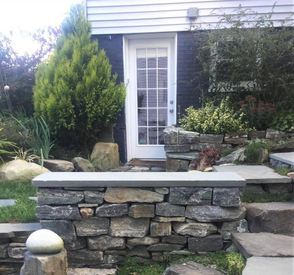 a cat sitting on a stone bench in front of a house at Garden Suite A Peaceful Oasis on Munjoy Hill in Portland