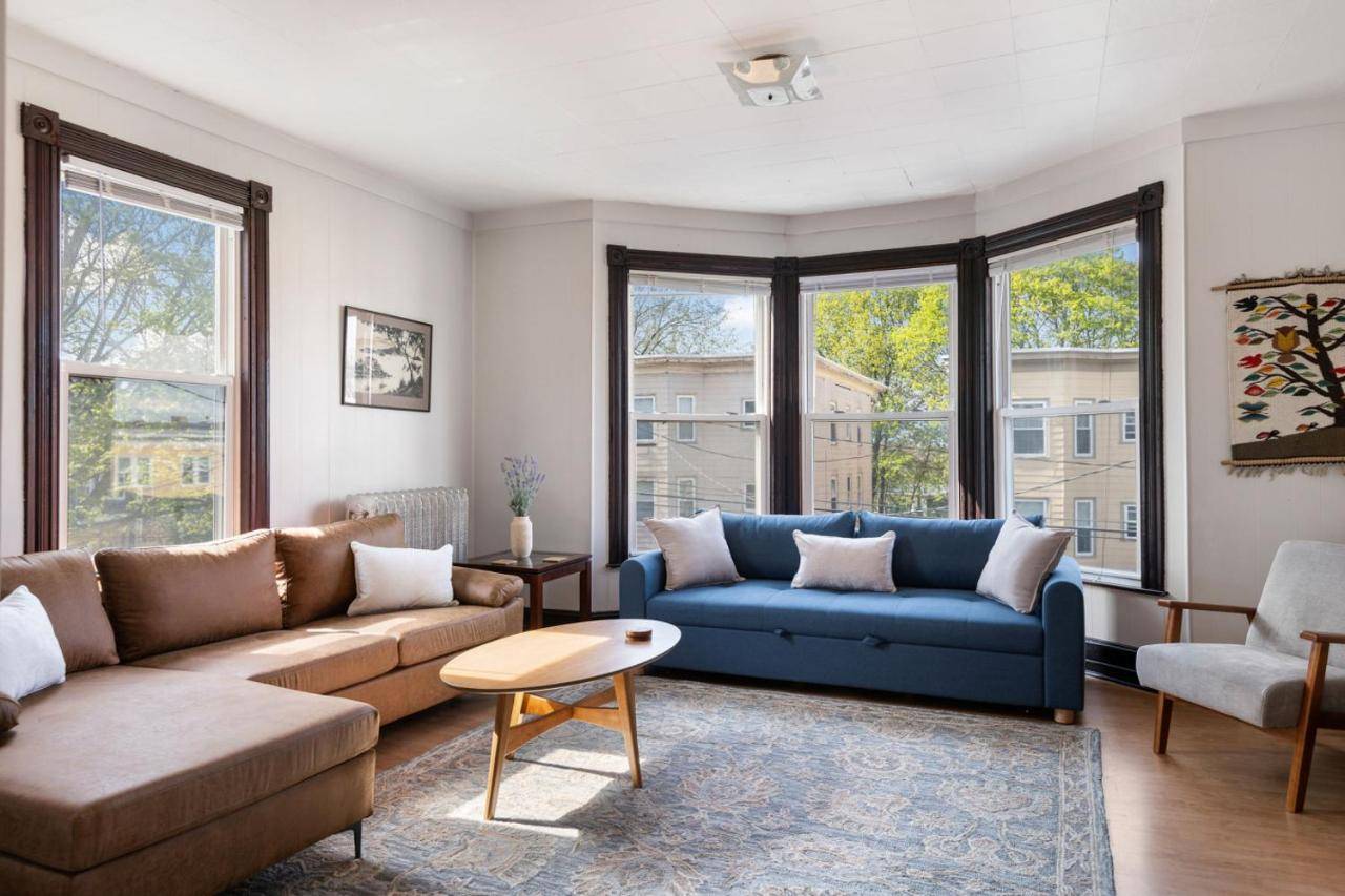 a living room with blue couches and windows at Knock on Wood - Airy Charm in Heart of Downtown in Portland