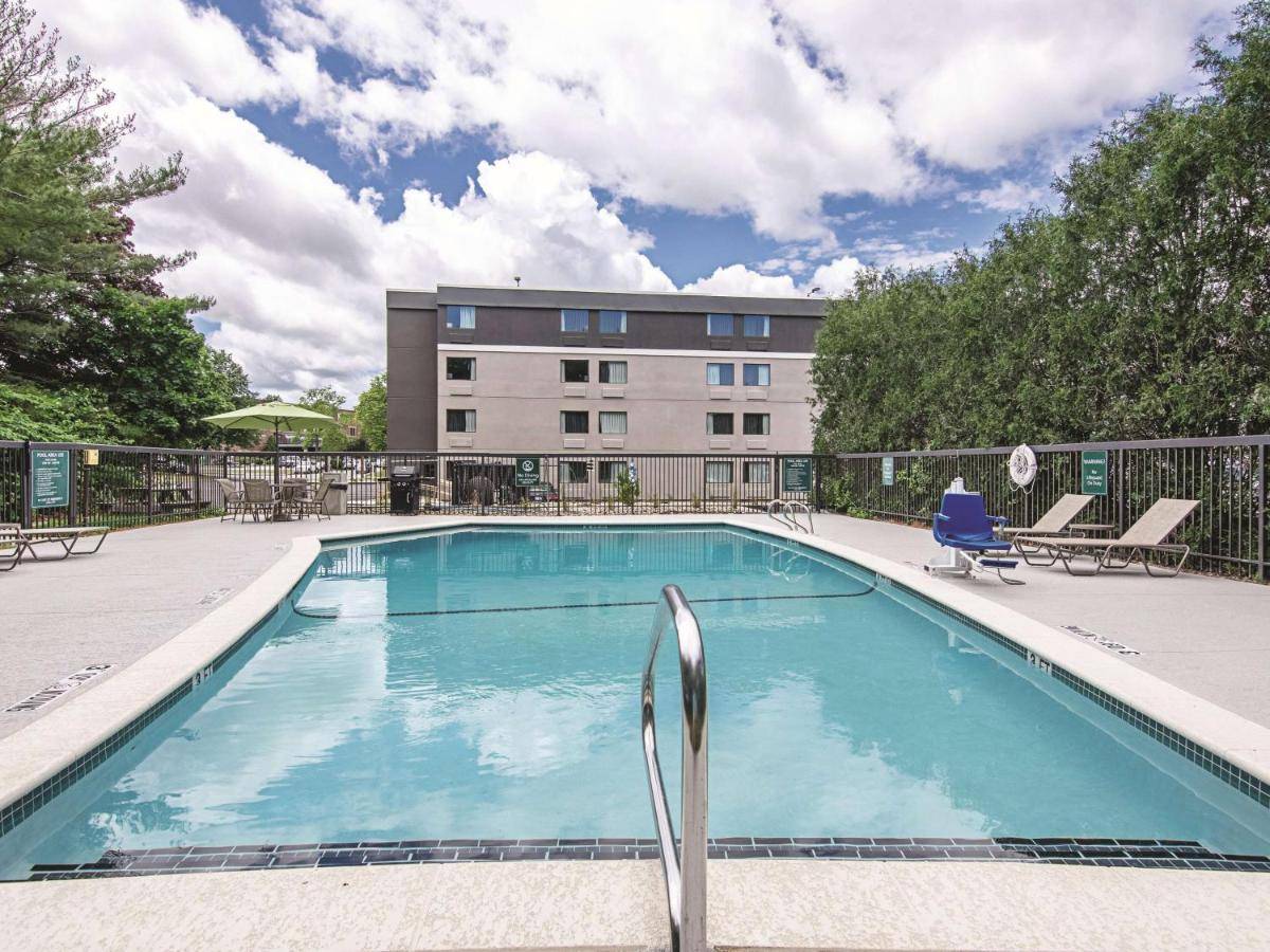a swimming pool with chairs and a building in the background at La Quinta Inn & Suites by Wyndham Portland DT Maine Med in Portland
