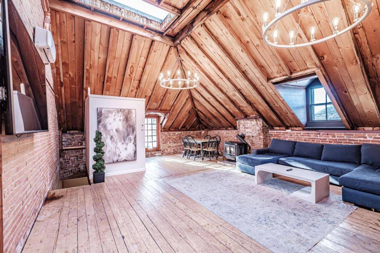 a living room with a blue couch and a brick wall at Lofty Ambition - Stunning West End Rooftop Retreat in Portland