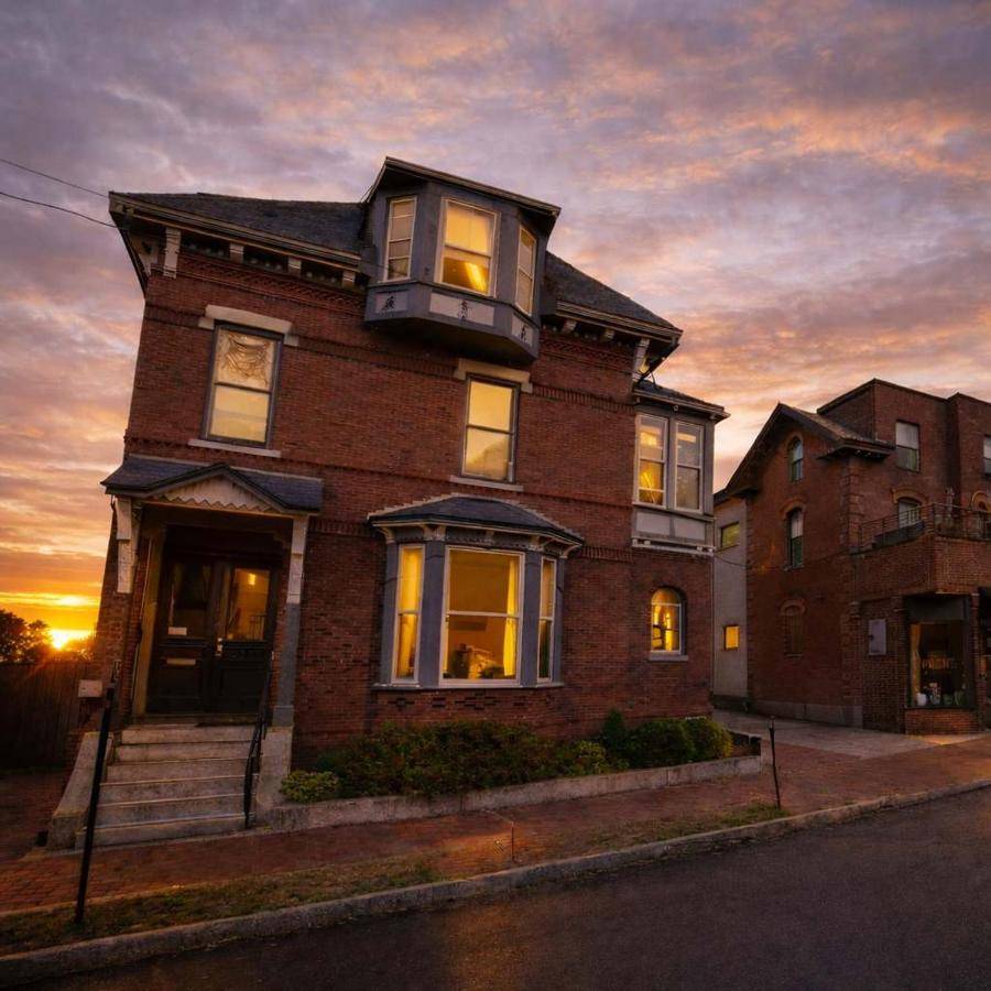 a large brick house with a sunset in the background at The Navigate Stays Portland Gem Steps to Old Port in Portland