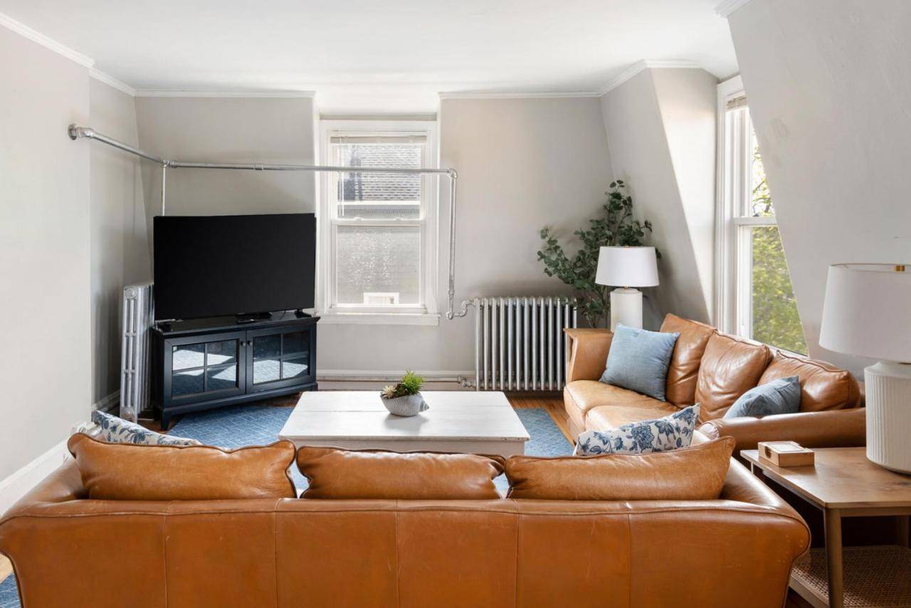 a living room with a brown leather couch at Skyline 138 Charming West End Mansard Penthouse in Portland