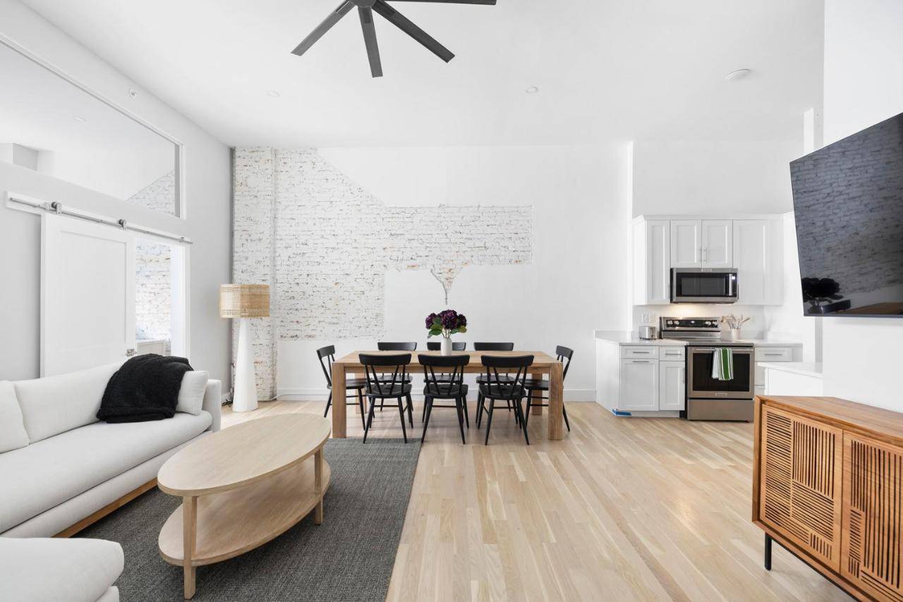 a white living room with a table and a kitchen at Spacious 2BR Old Port Loft, Steps from Waterfront in Portland