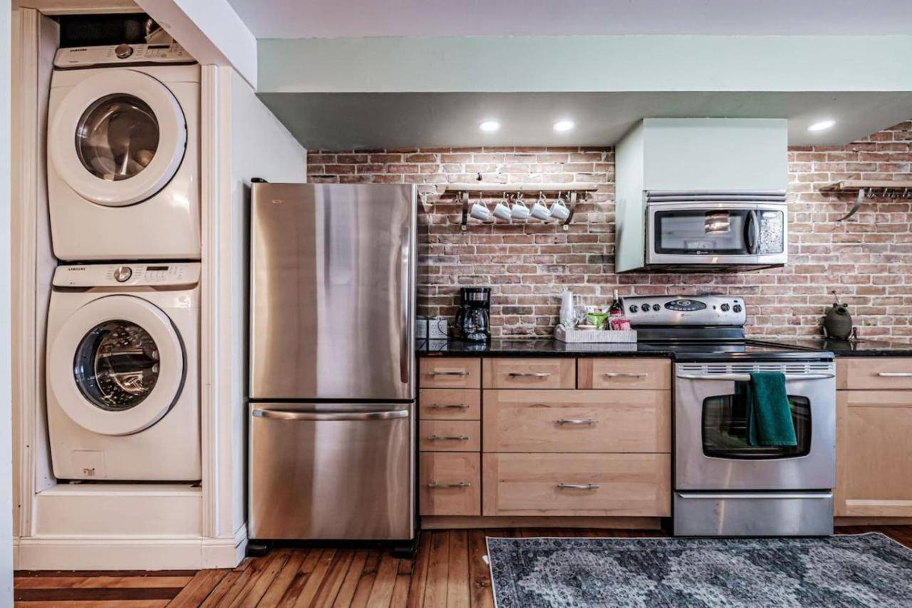a kitchen with stainless steel appliances and a brick wall at State of Charm - Historic West End Haven in Portland