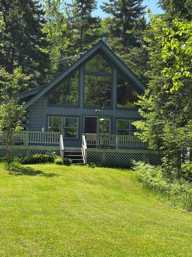 a house with a large window on a lawn at Outta Range Outta Range, A Cozy Log Home Retreat in Rangeley