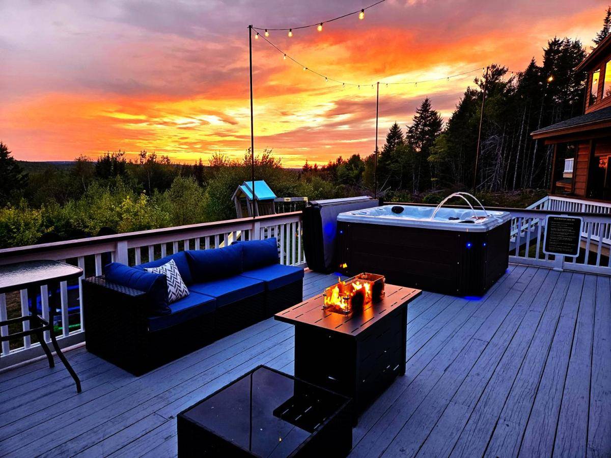 a deck with a couch and a hot tub at Bear Mountain Lodge. 560 Acre Wooded Estate. in Robbinston