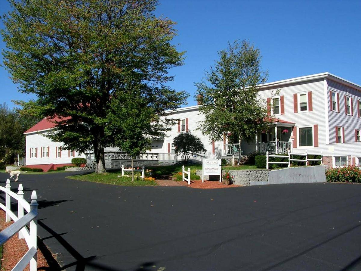 a white house with a tree and a white fence at Swift River Suites in Rumford