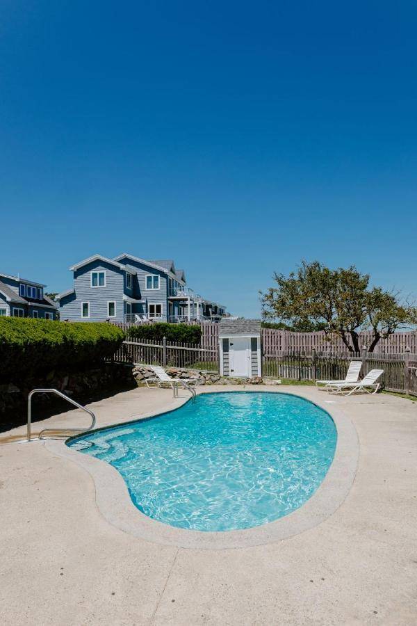 a swimming pool with chairs and a house in the background at Beauty on the Beach by Bayley Vacation Rentals in Saco