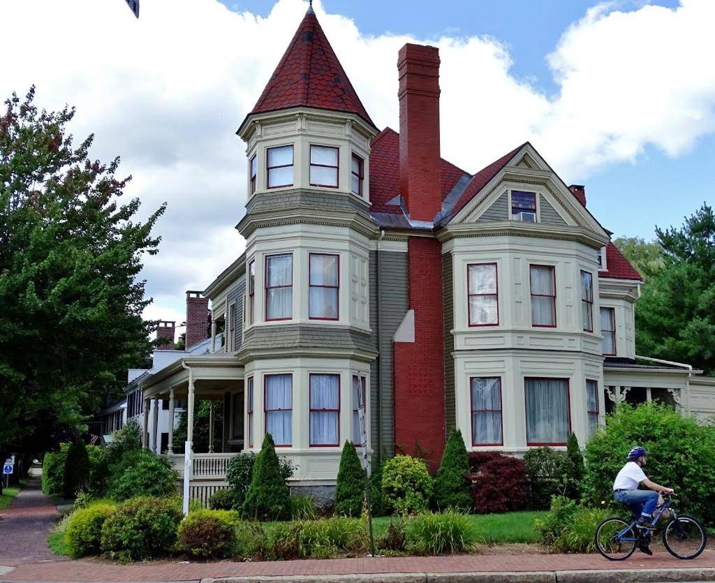 a person riding a bike in front of a house at The Gregory House - A Maine Victorian Mansion in Saco