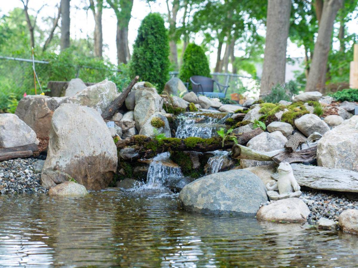 a garden with a pond with rocks and a waterfall at The Garden House in Saco