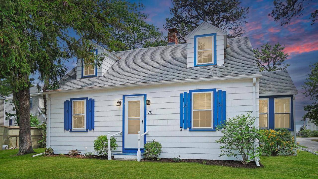a white house with blue shutters on it at Knotty Nauti by Bayley Vacation Rentals in Scarborough