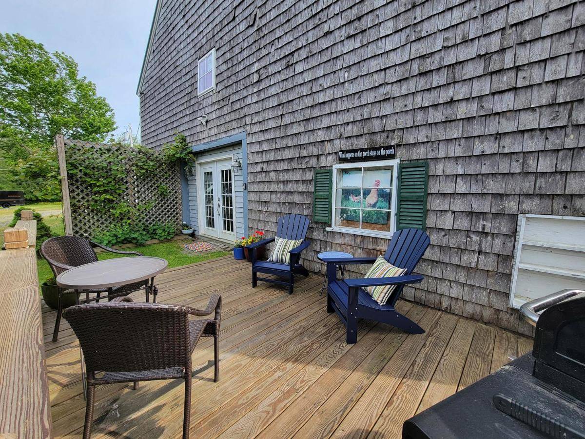 a wooden deck with chairs and a table and a window at The Nest and Captains Quarters in Searsport
